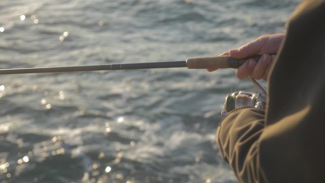 fisherman rolls up the reel