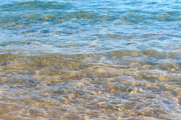 Clear water texture in blue and orange. Background of the ocean and the sea backlit by the sun. Soft waves. Natural water