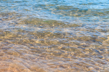 Clear water texture in blue and orange. Background of the ocean and the sea backlit by the sun. Soft waves. Natural water