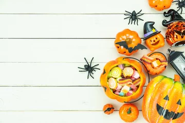 Foto op Aluminium Table top view aerial image of decorations Happy Halloween day background holiday concept.Flat lay objects to party pumpkins and spider with candy sweet on white wooden wallpaper.Copy space for text. © osabee
