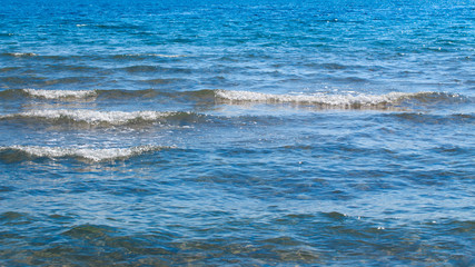 Clear water texture in blue and orange. Background of the ocean and the sea backlit by the sun. Soft waves. Natural water