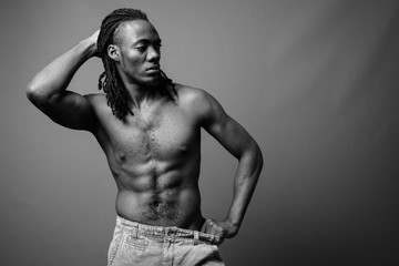 Young handsome African man shirtless against brown background