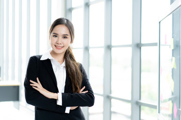 Portrait of beautiful and smart Asian businesswoman in formal suit standing beside window close up. Modern lifestyle and professional people concept.