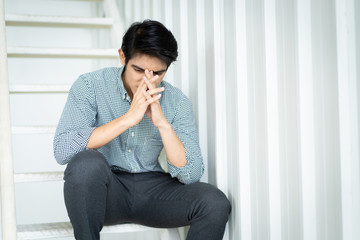 Hopeless Asian businessman sitting on the stairway. Stressed Asian businessman's portrait with copy space background.