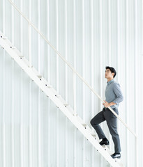 Young Asian businessman walking up the stair confidently.  Achievement and motivation in employment...