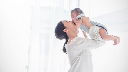 Portrait of asian mother lifting and playing with newborn baby, baby talking to mother. Health care...