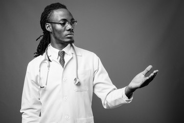 Young handsome African man doctor against brown background