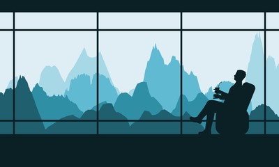 Man resting by the window with a view of the mountains. Silhouette of relaxed young man sitting in an armchair and dreaming at his future.