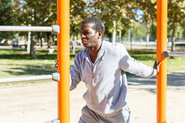 Obraz premium Young male training different exercises at chin-up bar in park outdoor