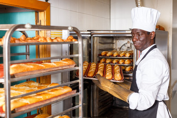 Baker putting baked bread on rack