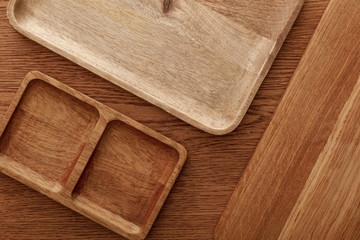 Fototapeta na wymiar top view of wooden dishes and cutting board on brown background