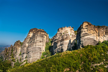 Monastery Meteora Greece. Stunning panoramic landscape. View of mountains and green forest against epic blue sky with clouds. UNESCO heritage object.