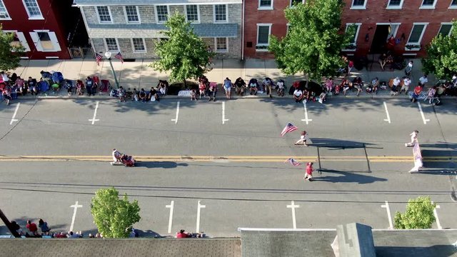 Static aerial of marchers carrying American flags during Independence Day Parade in Lititz Pennsylvania