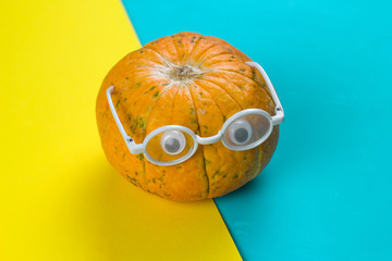 little funny pumpkin with eyes in glasses on a yellow and blue background