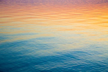 Foto op Aluminium Clear water texture in blue and orange. Background of the ocean and the sea backlit by the sun. Soft waves. Natural water © Alwih