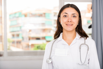 Obraz premium Young female practitioner in white uniform standing in clinic's office