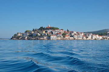 Fototapeta premium Sailing on motor boat on Adriatic sea with Primosten cityscape in the background. Vacation in Croatia