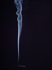 Steam of white smoke from burning aromatic stick, isolated on black background, close up view. Structure of smoke, brush effect. Abstract background. Burning incense for meditation and relaxation