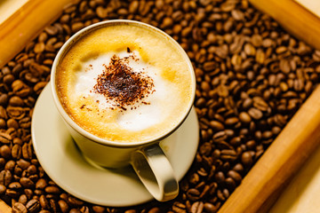 Cappuccino cup on roasted coffee beans.