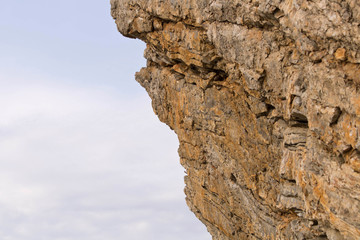 Part of a stone cliff against a blue sky. Selective focus.