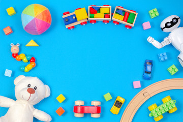 Kids toys background. White teddy bear, wooden train, toy car, robot, colorful blocks on light blue background