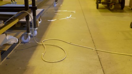 A low angle static footage showing a man walking over the wires laid on the floor. Concept of danger,hazard,workplace accident, precaution.
