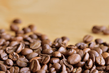 Roasted coffee beans scattered on a wooden surface close up