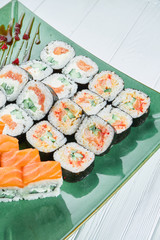 Close up view on set of assorted roll and sushi on green plate isolated on white wooden background. Sushi with salmon, eel. japanese sushi food