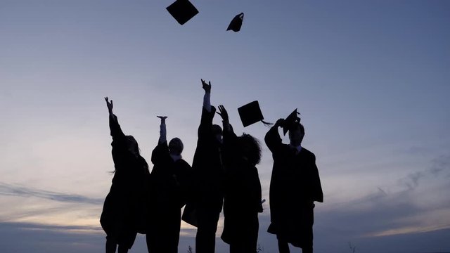 Silhouette of Diverse International Students Celebrating Graduation Tossing Caps in the air.