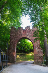 Fototapeta na wymiar ein steinernes altes Tor zur Mildenburg in Miltenberg umrahmt von der Natur vor einer Brücke