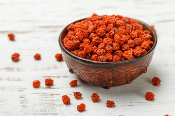 Dried Rowan berries in a ceramic bowl on a white table. Selective focus,  copy space