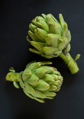 Obraz premium two green artichokes on a black background