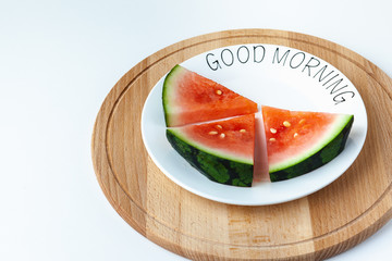 Watermelon lies on a plate with lettering Good morning, on a wooden tray. Super food for vegetarians. Suitable for banner, poster, web site, advertisement.
