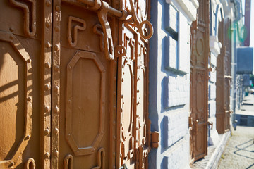 Metal door with wrought iron fence and the wall of the house on a Sunny day