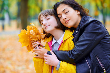 woman closing eyes with autumn leaves in city park, outdoor portrait