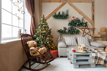 Christmas morning in the bright living room. Homemade gingerbread house on background room decorated for Christmas.