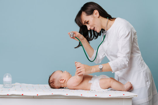 Doctor Exams Baby With Stethoscope On A Special Table Over Blue Background