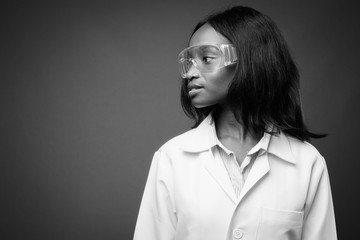 Young beautiful African Zulu woman doctor wearing protective glasses against brown background