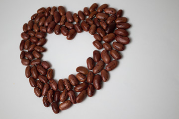 Symbol of love and health, heart. Red beans are scattered on the table in the shape of a heart....