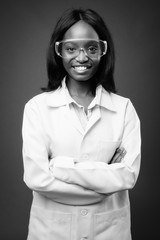 Young beautiful African Zulu woman doctor wearing protective glasses against brown background