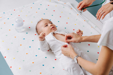 Mother with her little infant baby during a visit to a doctor over blue