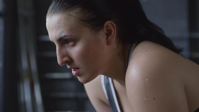 Close up view of sweaty female athlete heavily breathing and shaking chalk powder off her hands after weightlifting in gym
