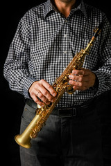 Naklejka premium soprano saxophone in hands on a black background