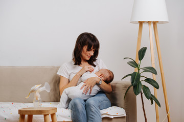 Caucasian mother is decently breastfeeding her baby, without exposing herself.