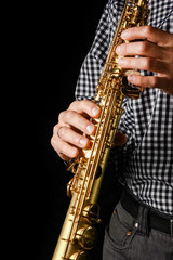 Naklejka premium soprano saxophone in hands on a black background