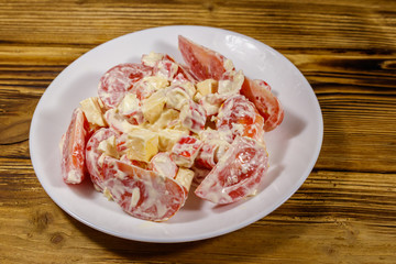 Tasty salad with crab sticks, cheese, tomato and mayonnaise on wooden table