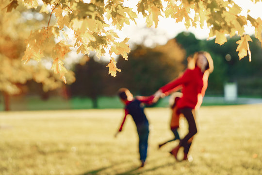 Cute family in a autumn park. Happy mother with little kids. Family playing on yellow leaves. Golden autumn.