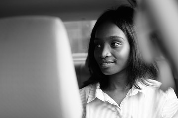 Young beautiful African Zulu businesswoman riding inside the car