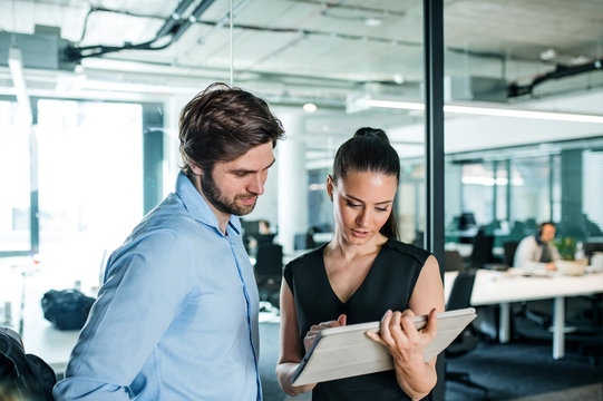 Young businesspeople with tablet in an office, working.