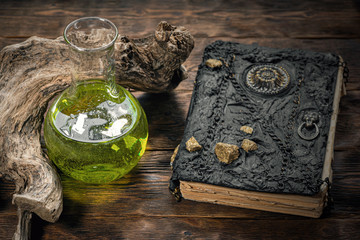 Magic book and magic potion bottle on brown wooden table background. Witchcraft. Witch doctor.